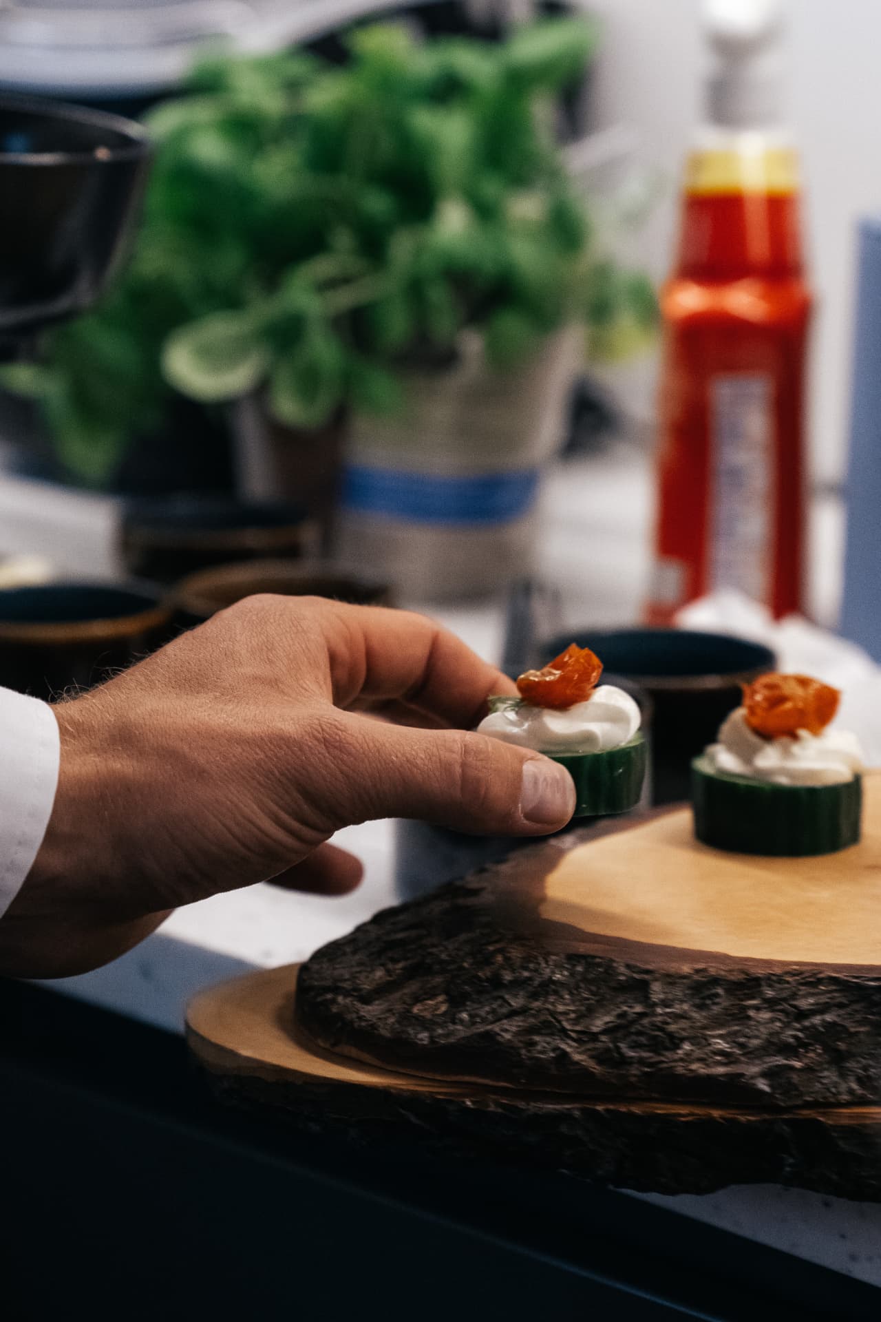 Hand beim Platzieren eines Gurken-Canapés auf einem Servierbrett