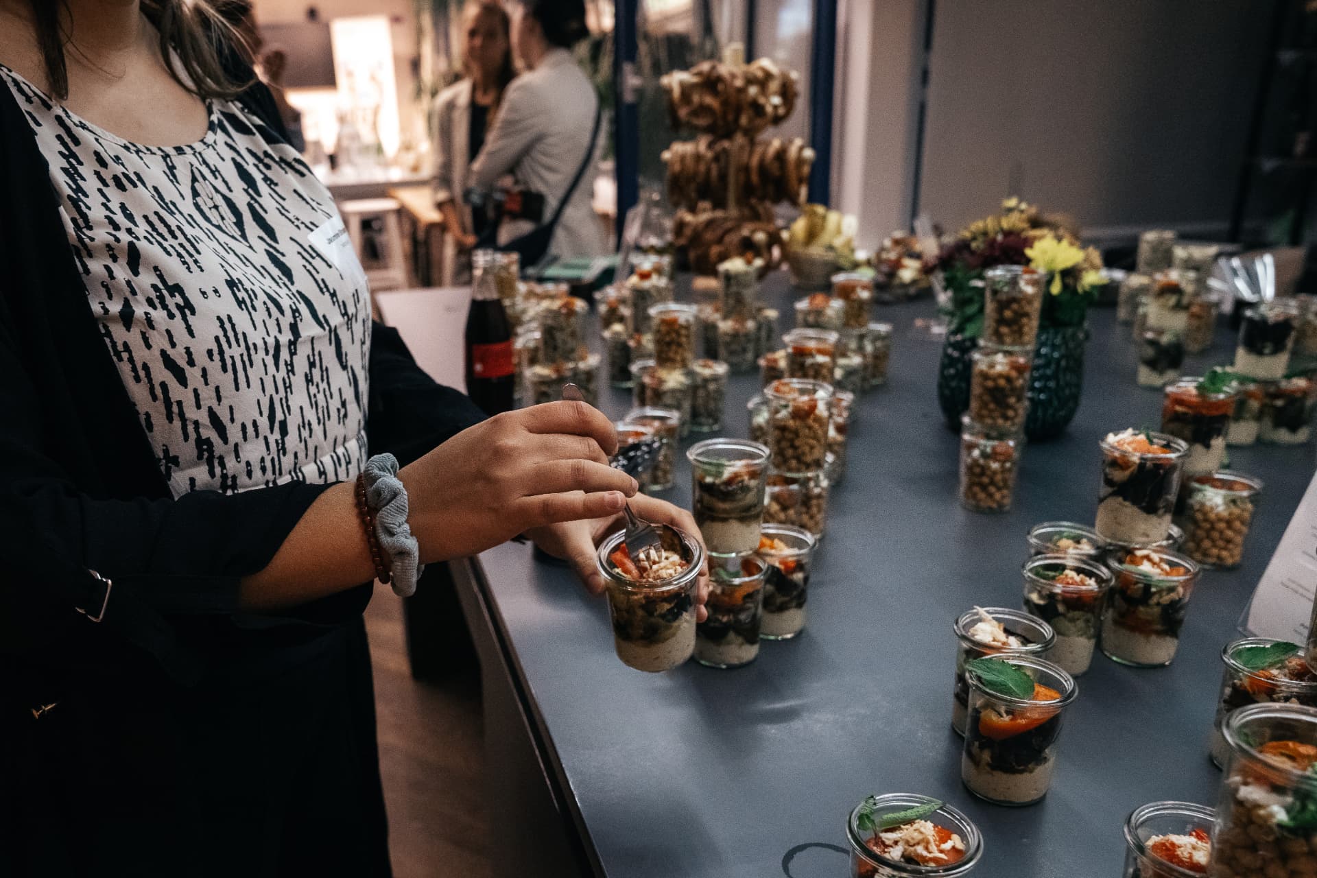 Gast mit einem Fingerfoodglas an einem aufgebauten Buffet