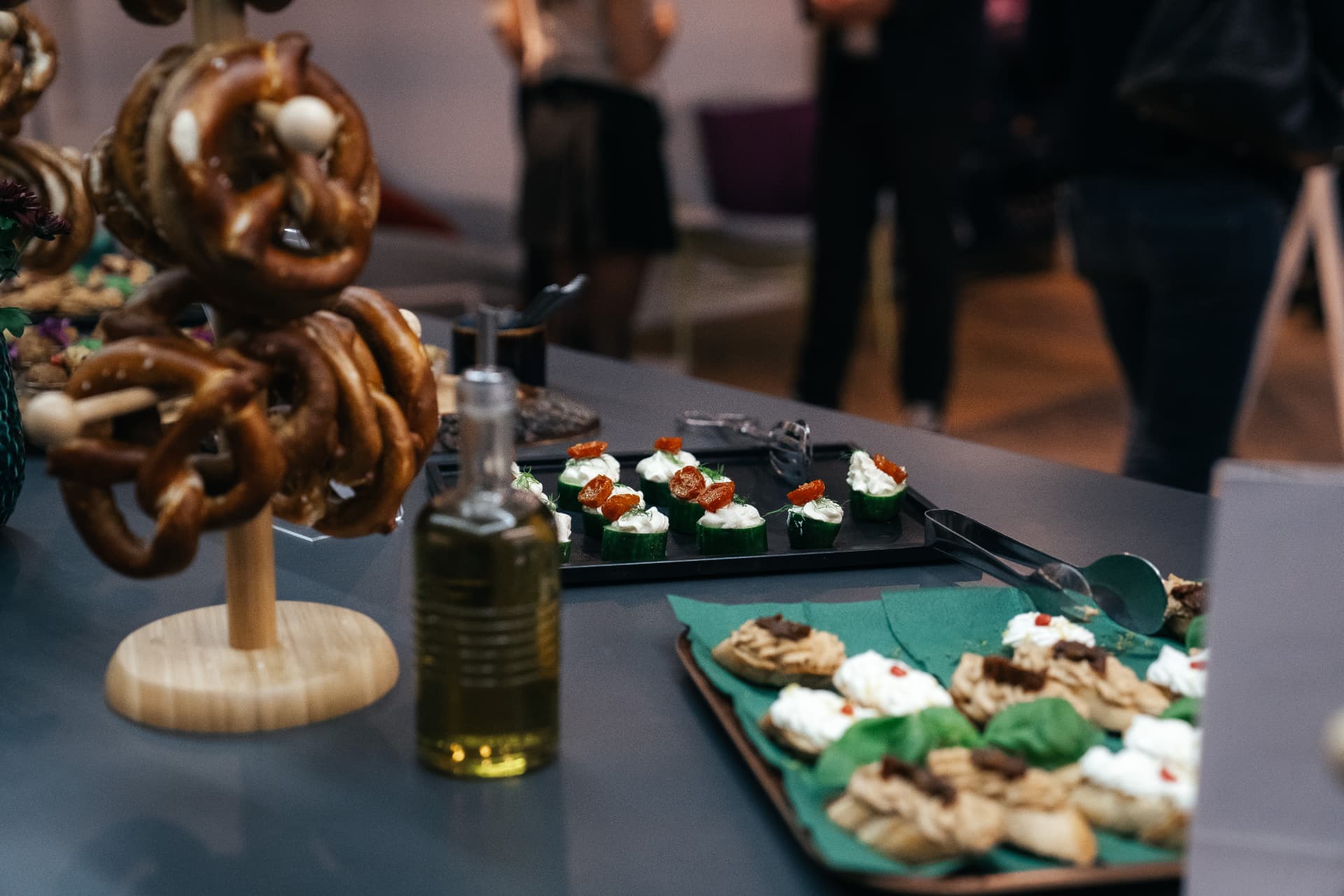 Eventbuffet mit Brezen und Fingerfood vor Gästen im Hintergrund
