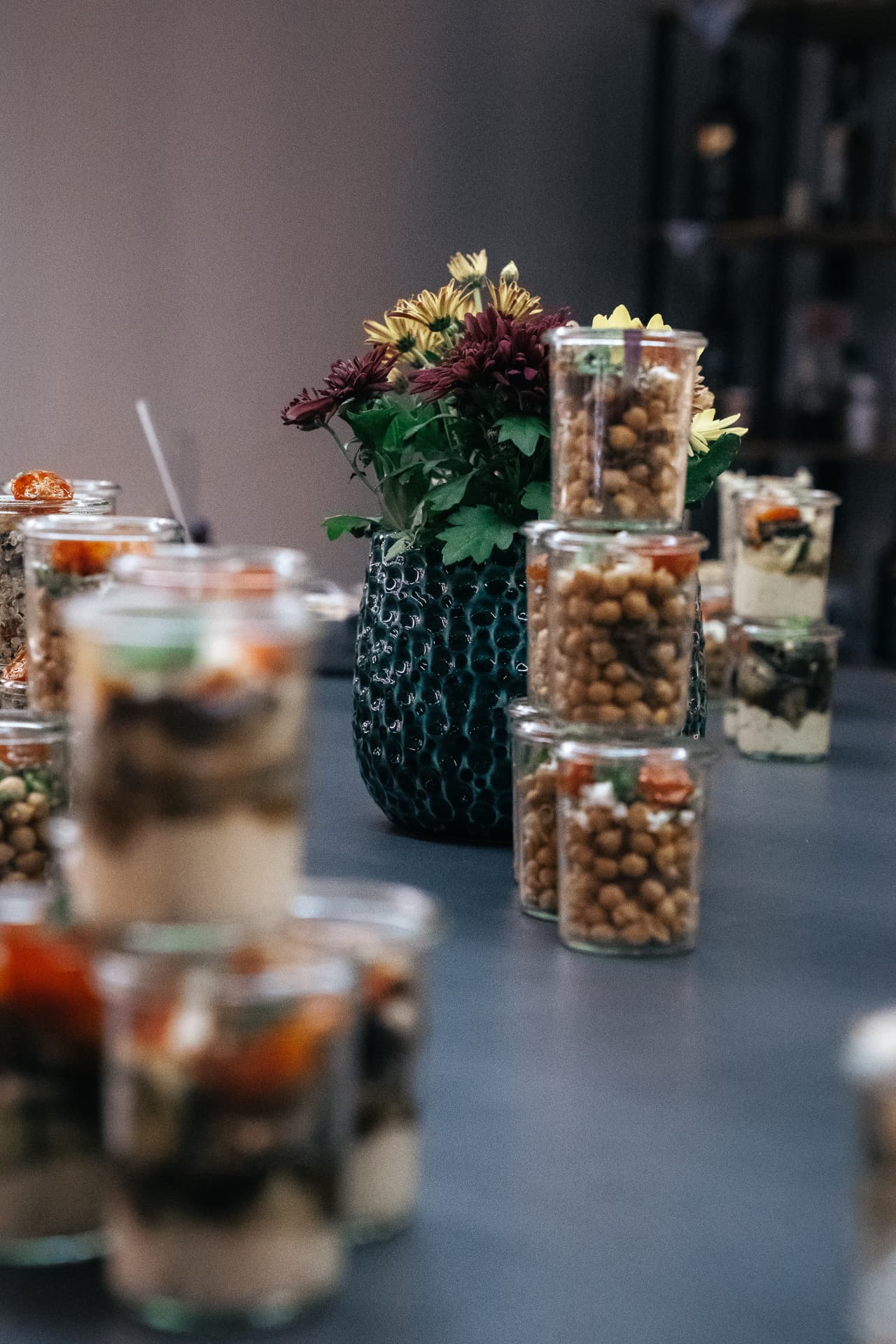 Blumen und gestapelte Fingerfoodgläser auf einem Buffet
