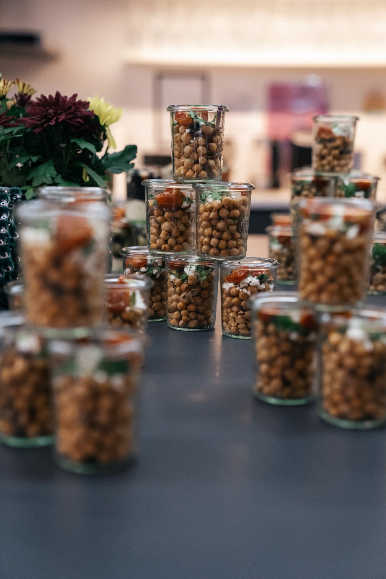 Gestapelte Fingerfoodgläser mit Blumen im Hintergrund